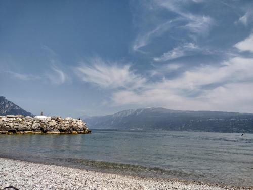 a beach with a rocky shore with mountains in the background at Casa Gabri in Toscolano Maderno