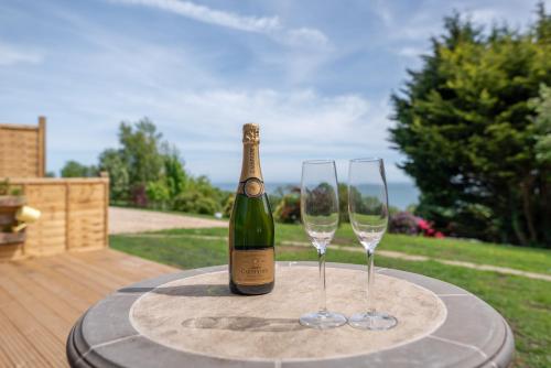 a bottle of wine and two wine glasses on a table at The Jolly Lodge-Sea Views-Free Parking in Lyme Regis