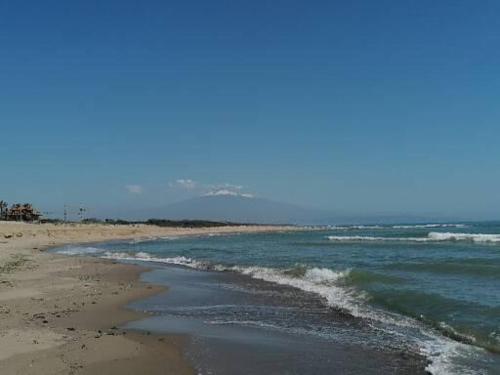 a beach with the ocean and a mountain in the background at Alexia in Agnone Bagni