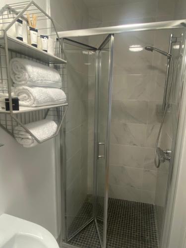 a bathroom with a glass shower stall with towels at Racecourse View in Listowel