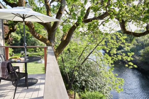 a patio with a table and an umbrella next to a river at Milliken Creek Inn in Napa