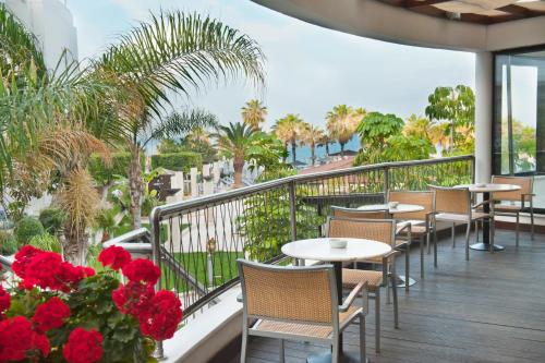 a balcony with tables and chairs and red flowers at Louis Ledra Beach in Paphos City