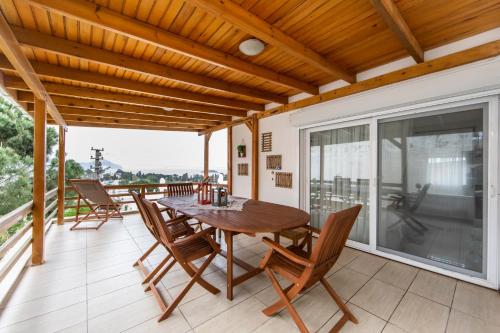 patio con mesa de madera y sillas en el balcón en Summer Private Villa with Garden and Private Pool, Within Walking Distance to the Sea in Bodrum Gumusluk, en Bodrum City