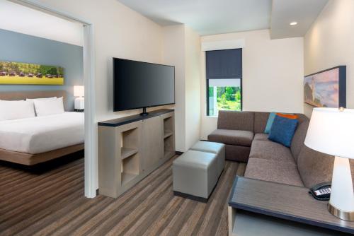 a hotel room with a couch and a bed and a television at Hyatt House Tallahassee Capitol University in Tallahassee