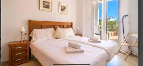 a bedroom with a large white bed with a window at Bonito holiday, La Torre Golf Resort in Murcia