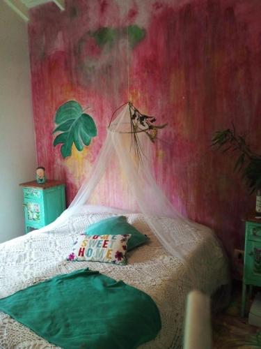 ein Schlafzimmer mit einem Bett mit einer grünen Wand in der Unterkunft los agapantus in Ingeniero Maschwitz