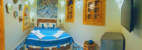 sypialnia z łóżkiem z niebieską i białą pościelą w obiekcie Riad Milal w mieście As-Suwajra
