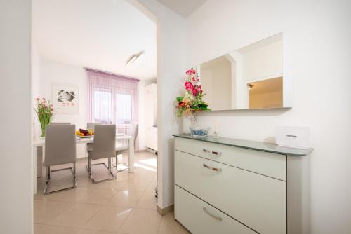una cocina con armarios blancos y una mesa con sillas. en REA en Rijeka