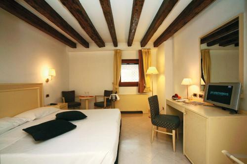 a bedroom with a bed and a desk with a computer at Hotel Giudecca Venezia in Venice