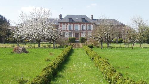 a house with a row of hedges in a field at Clos Florésine B&B in Venette
