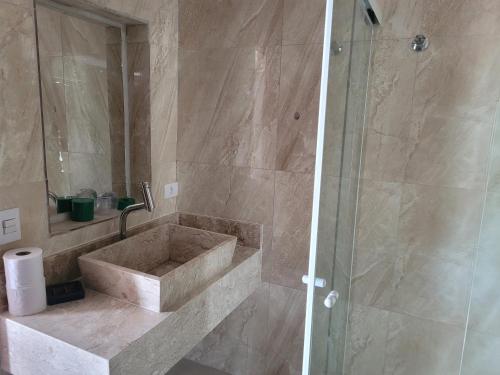 uma casa de banho com um lavatório e um chuveiro em Suíte Luxo Refúgio das Ostras no Guarujá