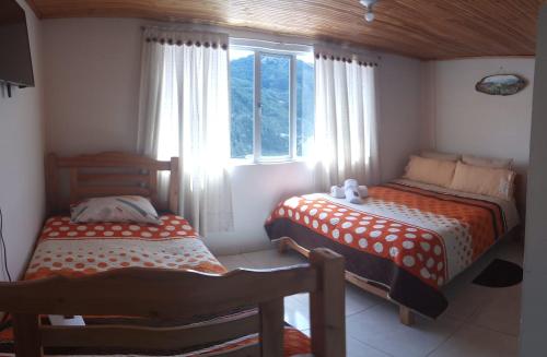 een slaapkamer met 2 bedden en een raam bij Los Recuerdos de Florito y Leo in Monguí