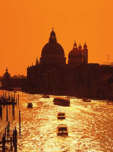 a city with boats in the water at sunset at Hotel Giudecca Venezia in Venice