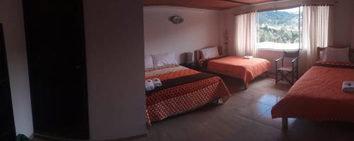 a hotel room with two beds and a window at Los Recuerdos de Florito y Leo in Monguí