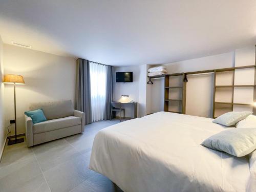a bedroom with a large white bed and a chair at Hotel Quatre Llunes in Santa Pola