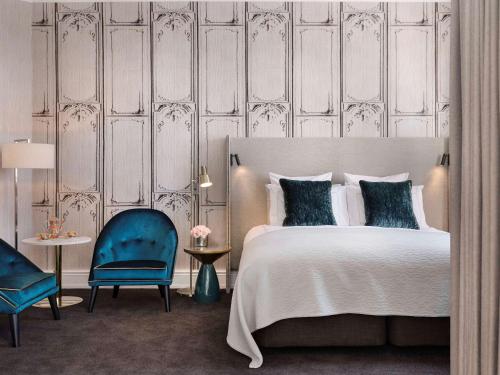 a bedroom with a bed and a blue chair at Fable Auckland, MGallery in Auckland
