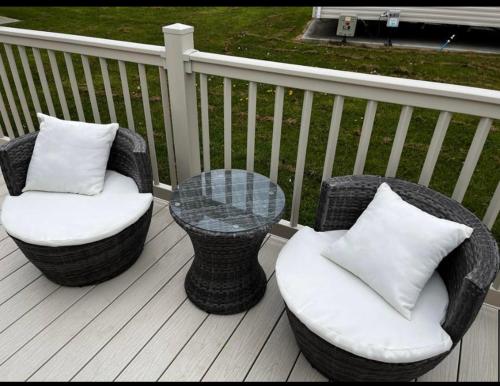 two wicker chairs and a table on a deck at Cosy caravan in Hull