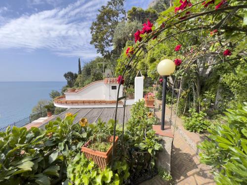 a garden with flowers and a boat in the background at Due Relais - Panoramic Sea View Suites in Vietri sul Mare