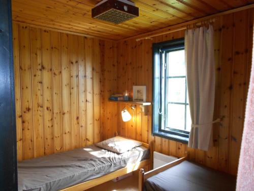 a bedroom with a bed in a wooden wall at Holiday Home Långberget in Sysslebäck