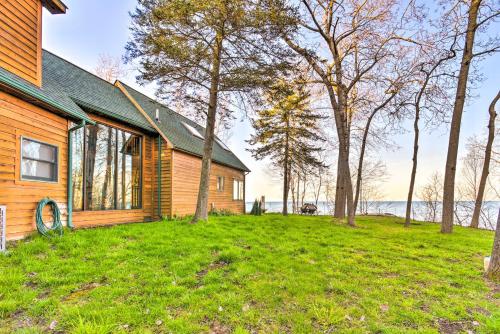 a wooden house on a grassy field next to trees at Lakefront Applegate Retreat with Private Beach! in Applegate