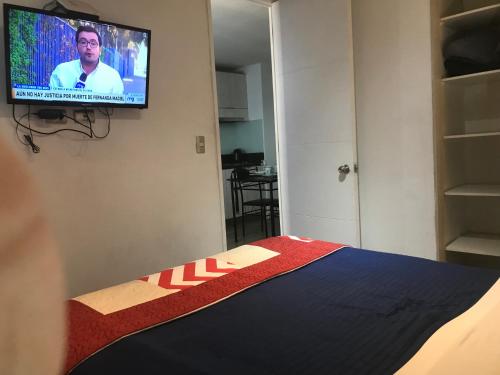 een slaapkamer met een bed en een televisie aan de muur bij Apartment Relocation 1 Dormitorio in Santiago