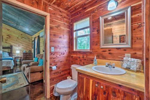 a bathroom with a toilet and a sink in a log cabin at Updated Studio Cabin in Ozark with Yard and Mtn View in Ozark