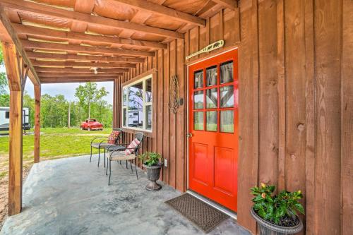 a wooden cabin with a red door on a patio at Updated Studio Cabin in Ozark with Yard and Mtn View in Ozark