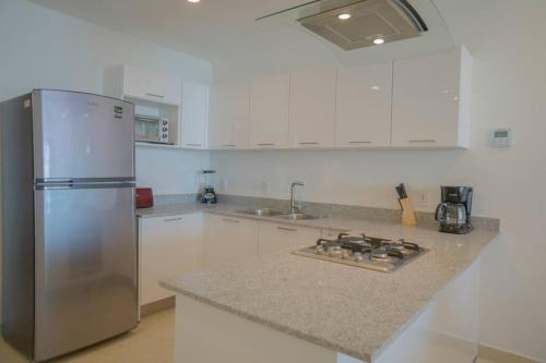 a kitchen with a stainless steel refrigerator and white cabinets at Camino al Mar a pie de playa in Mazatlán