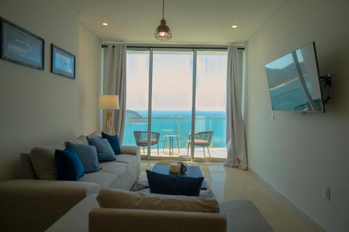 a living room with a couch and a large window at Camino al Mar a pie de playa in Mazatlán