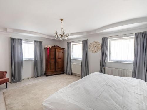 a bedroom with a bed and windows and a chandelier at Luxurious holiday home with a nice private garden in Ditscheid