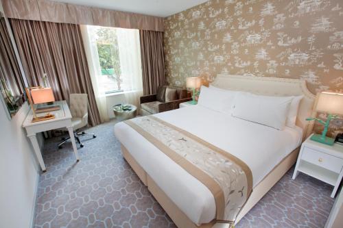 a hotel room with a large bed and a desk at Dorsett Shepherds Bush London in London