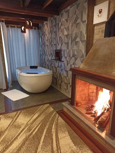 a bathroom with a bath tub next to a fireplace at CHALÉS LUAR DO PICO in Santo Antônio do Pinhal