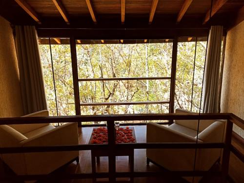 a room with two chairs and a large window at CHALÉS LUAR DO PICO in Santo Antônio do Pinhal