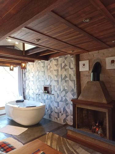 a large bathroom with a tub and a fireplace at CHALÉS LUAR DO PICO in Santo Antônio do Pinhal