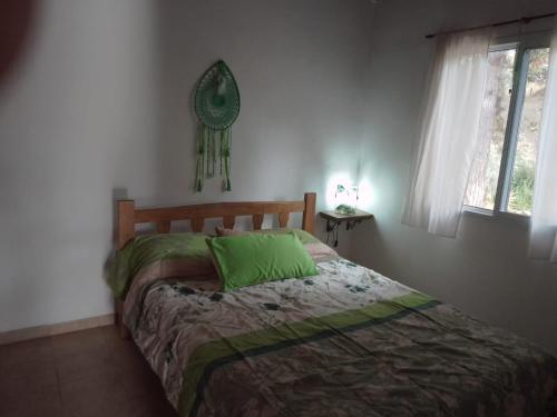 Un dormitorio con una cama con almohadas verdes. en Espejo de Hadas - Terrafirme, en Villa Yacanto