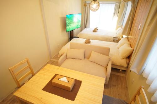 a small room with a couch and a bed and a table at 北新宿ウッドウォールステイ in Tokyo