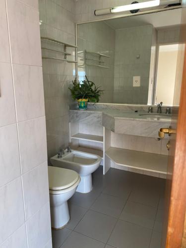 Un baño con lavabo, inodoro y espejo. en Departamento Mayoral, en Salta
