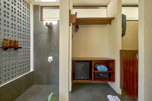 een badkamer met een kleine tv in een kamer bij Ama-Lurra Resort in Gili Air