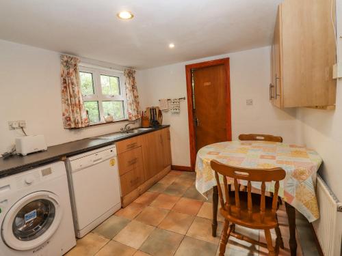 a kitchen with a table and a washing machine at Gortagown Cottage in Sneem