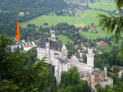 a castle on a hill with a red arrow at Hotel Garni Schlossblick in Hohenschwangau