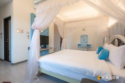 a bedroom with a white bed with a canopy at 幸福來了-近花蓮火車站 寵物友善 電梯民宿 in Hualien City