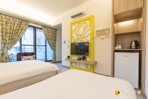 a hotel room with two beds and a tv at 幸福來了-近花蓮火車站 寵物友善 電梯民宿 in Hualien City