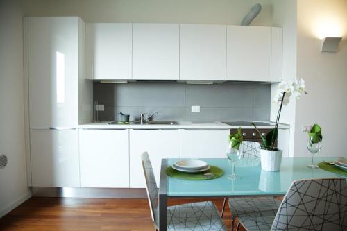 a kitchen with white cabinets and a blue table at Residence Milano Bicocca in Milan