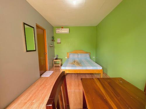 sypialnia z łóżkiem w zielonej ścianie w obiekcie Ananas Guesthouse w mieście Moalboal