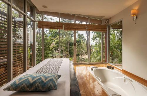 a bathroom with a large tub and a large window at Pakasai Resort - SHA Extra plus in Ao Nang Beach