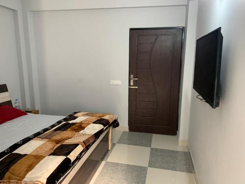 a bedroom with a bed and a television and a door at IMBUE STAYS in Dehradun