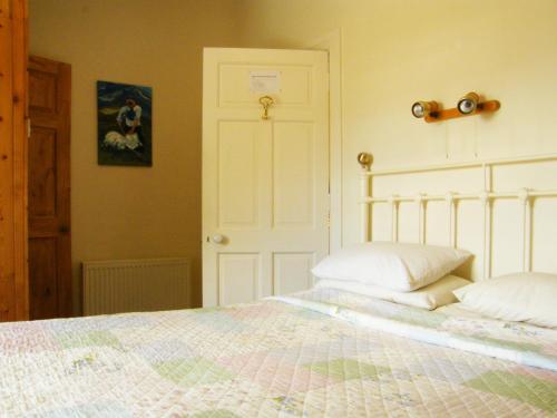 a bedroom with a large bed with white sheets and pillows at Druid Cottage in Kenmare