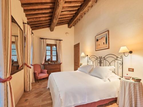 a bedroom with a white bed and a chair at Charming House in Tuscany with Pool in Monte Castelli