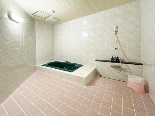 a bathroom with a green tub and a shower at Hotel ARUN-Adult Only in Abashiri