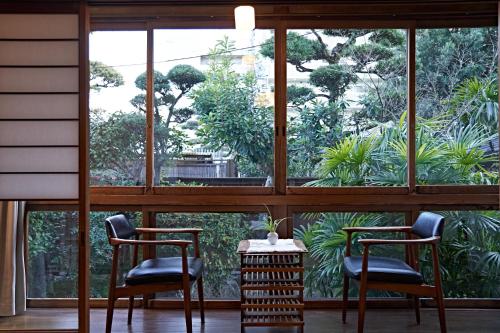 two chairs and a table in front of a window at Yamada Bessou くつろぎの温泉宿 山田別荘 in Beppu